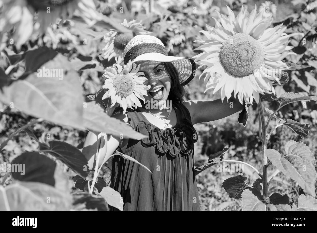 Grande piante. Fiore giallo di girasole. Felice infanzia. Bella ragazza indossare paglia cappello estate in campo. Ragazzo grazioso con fiore. Bellezza d'estate Foto Stock