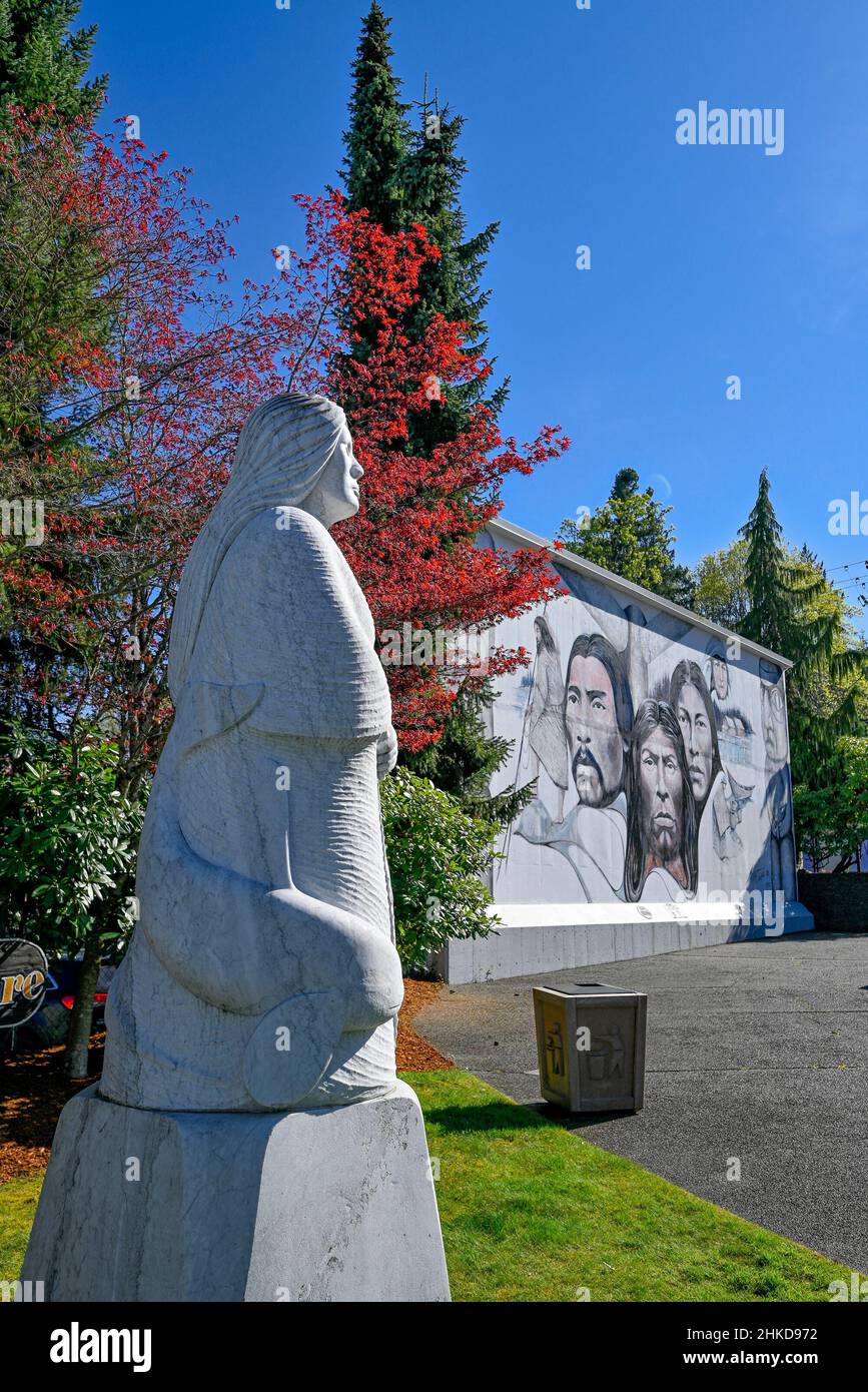Scultura in pietra Spirit of the Earth di Daniel Cline e murale Native Heritage di Paul Ygartua, Chemainus, British Columbia, Canada Foto Stock