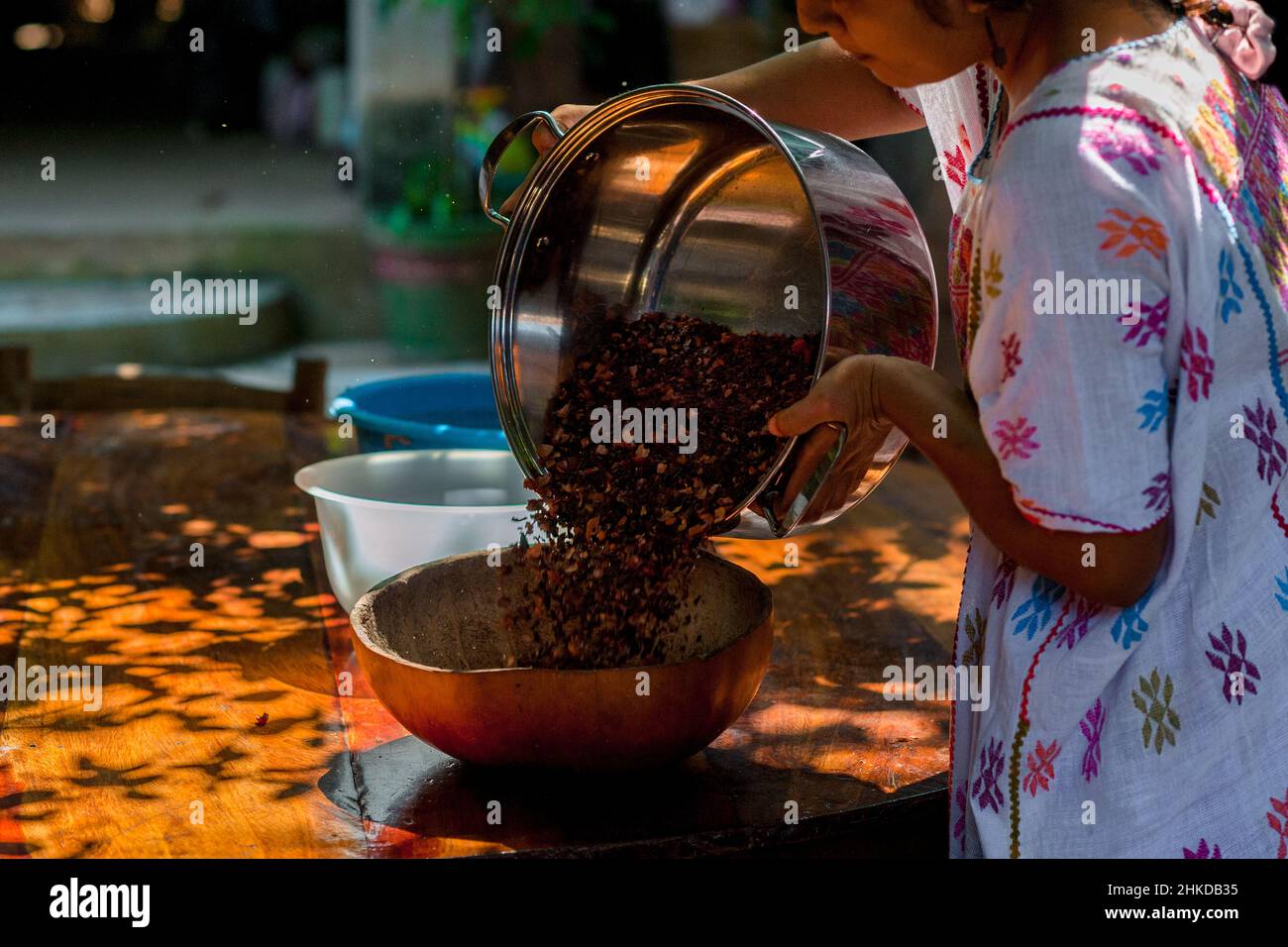 Una donna indigena getta i fagioli di cacao schiacciati da una pentola in una ciotola per la vinatura nella produzione artigianale di cioccolato in Xochistlahuaca, Messico. Foto Stock