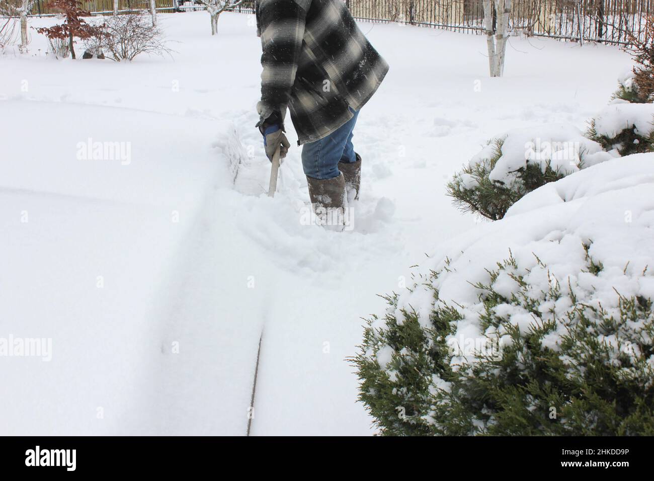 Un uomo libera la neve da una piscina all'aperto in un cortile privato. Manutenzione della piscina d'acqua in inverno. Foto Stock