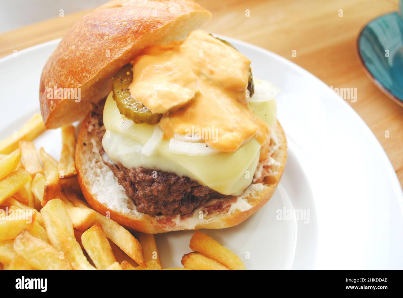 Delizioso hamburger di manzo con formaggio, cipolle, sottaceti e condimento Thousand Island Foto Stock