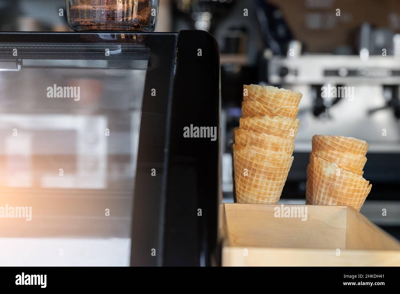 Molti coni di cialda cotti vuoti cotti e tazze di carta per gelato impilati al banco espositore della vetrina di Street food takeaway cafe' window. Dolci e dessert Foto Stock