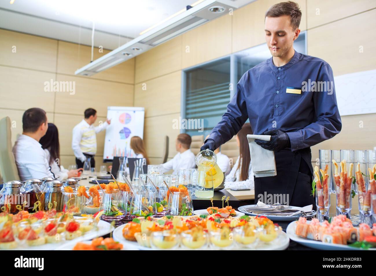 Un giovane cameriere versa delle bevande per il catering Foto Stock