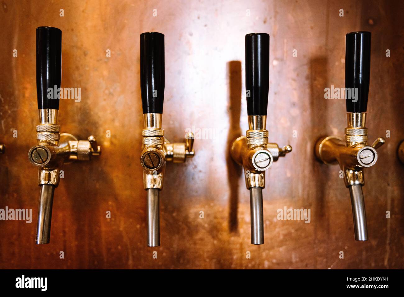 birra spillare molti in una fila bar interno in rame parete Foto Stock