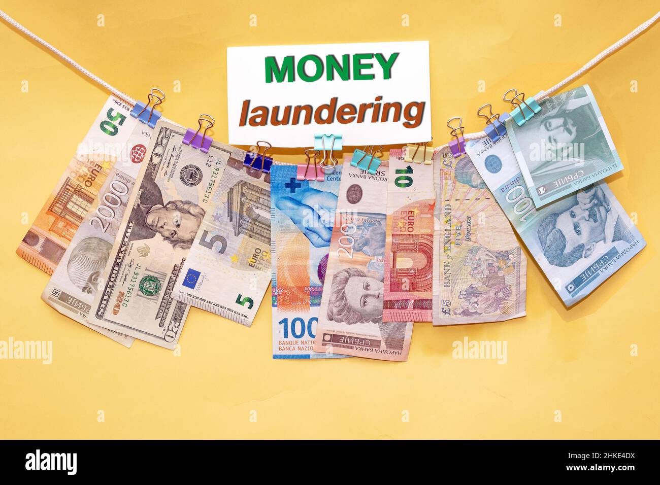 Banconote internazionali su una stringa che illustra il reato di riciclaggio di denaro Foto Stock