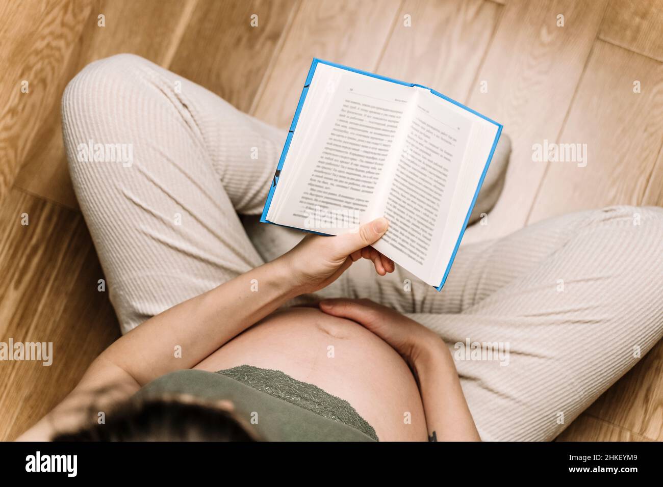 Una donna incinta sta leggendo un libro. Riposo, tranquillità e relax durante la gravidanza, hobby, tempo libero. Foto di alta qualità Foto Stock