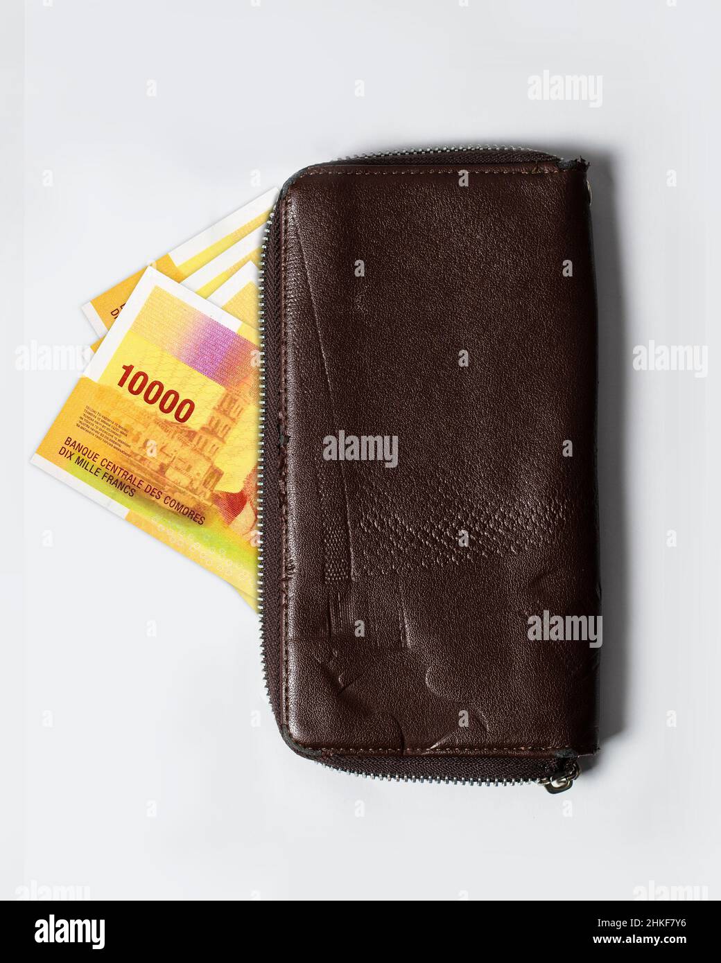 10000 il franco comoriano prende appunti all'interno di una borsa. Valuta comoriana che fuoriesce da una borsetta di pelle marrone Foto Stock