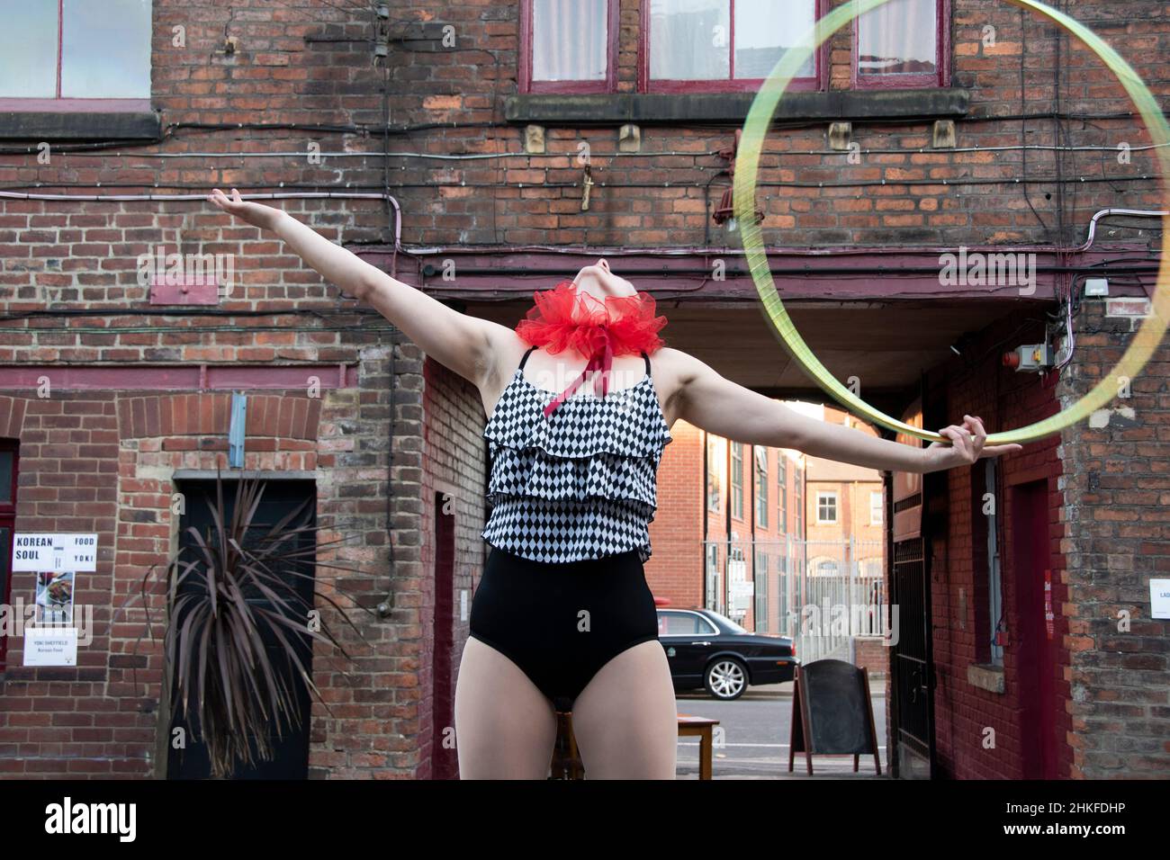 Sheffield, Regno Unito - Giugno 22: Un circo trucchi esecuzione donna su palafitte giocoleria con luppolo rotola un cerchio attraverso il suo petto 3 di 3 Foto Stock