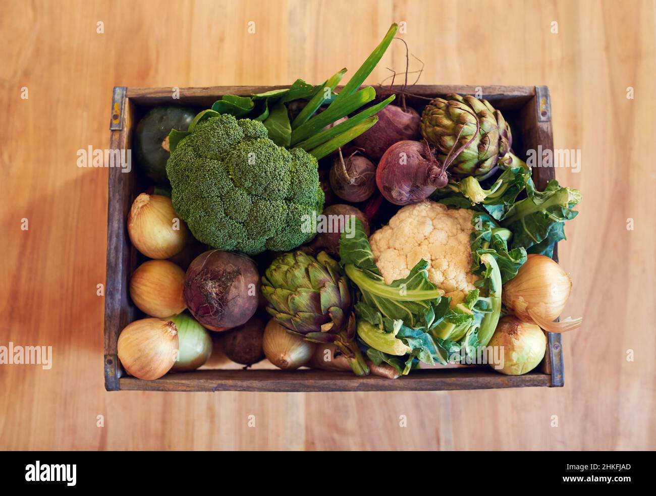 Prendi la tua scelta di verdure fresche. Shot di una varietà di verdure in una cassa su un tavolo. Foto Stock