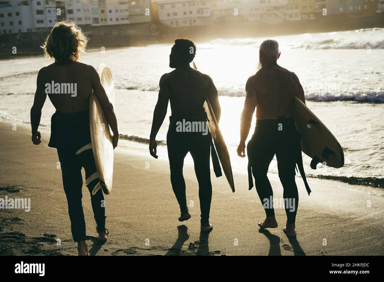 Amici di surfer multi generazionale divertirsi mentre navigano sulla spiaggia - Focus on left man Foto Stock