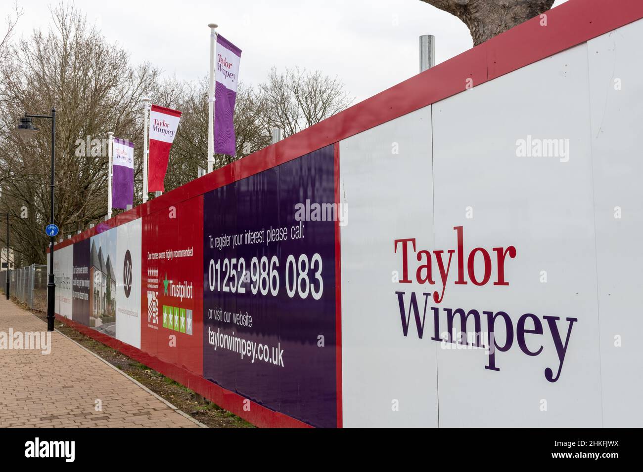 Taylor Wimpey ha le bandiere e gli hoardings intorno al nuovo sviluppo domestico a Wellesley, Aldershot, Hampshire, Inghilterra, Regno Unito Foto Stock