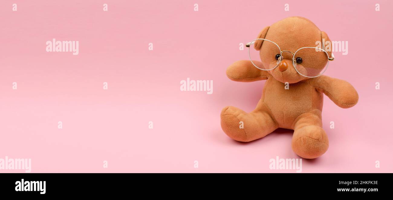 Orsacchiotto in occhiali per la visione su sfondo rosa Foto Stock