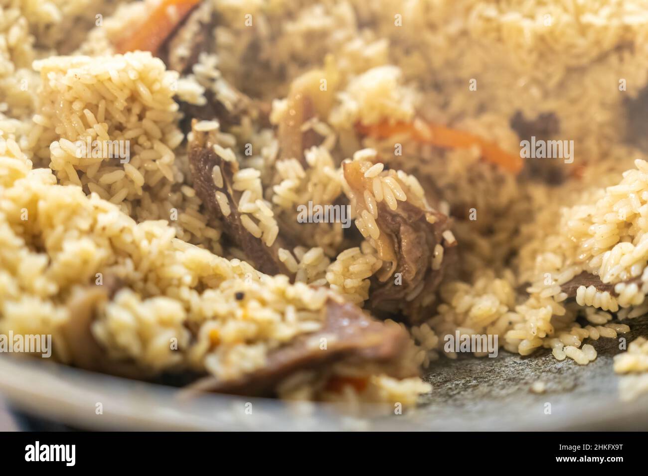 Messa a fuoco selettiva. Grande calderone con riso appena cotto. Una serie del processo di cottura pilaf in un enorme calderone a fuoco aperto. Pilaf appetitoso Foto Stock