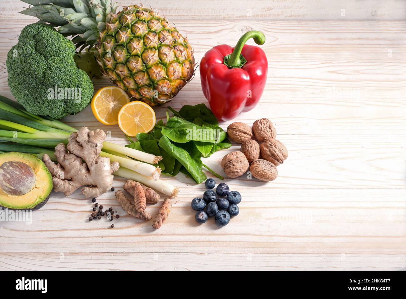 Cibo vegetariano con effetto antinfiammatorio e antiossidante, disposizione di verdure, noci, frutta e spezie su un fondo di legno chiaro con co Foto Stock