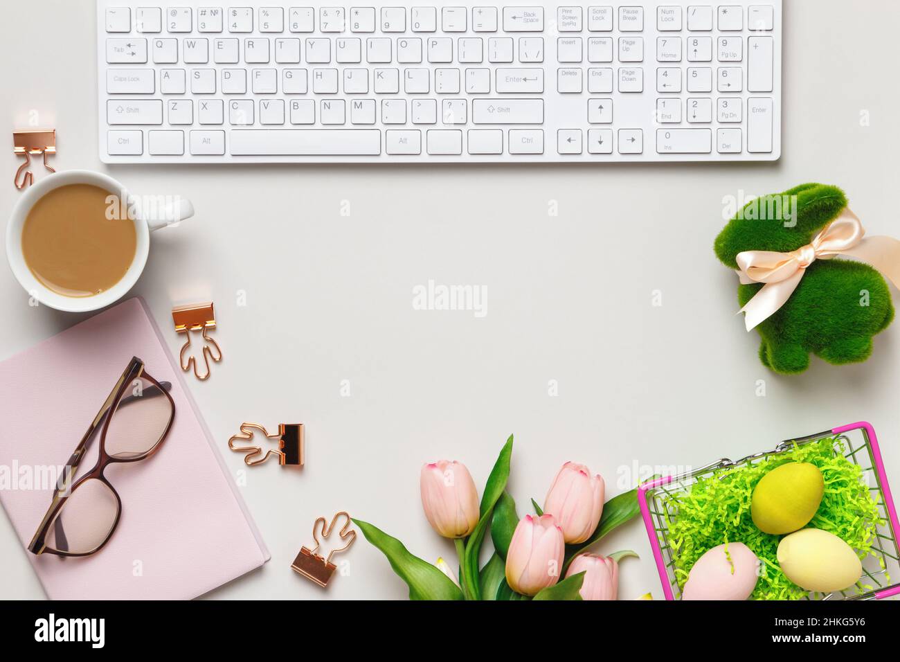 Desktop. Bicchieri tazzine da caffè tastiera blocco note su un tavolo con decorazioni pasquali. Vista dall'alto dello spazio di copia a disposizione piatta Foto Stock