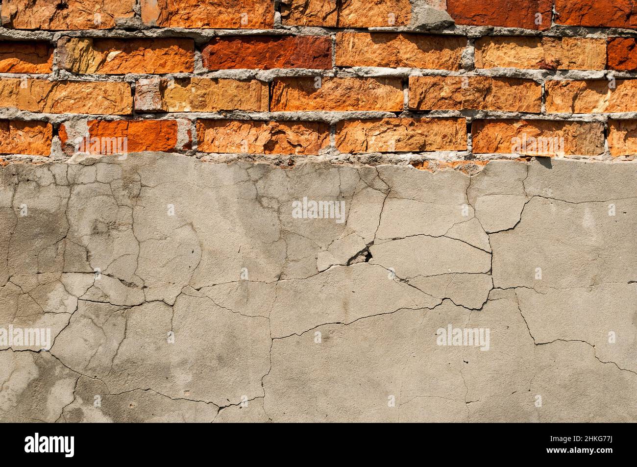 Vecchia parete di mattone con gesso caduto via. Sfondo di crack muro texture Foto Stock