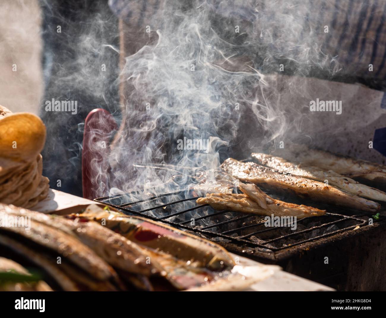 Venditore arrostire il pesce sgombro alla griglia a Istanbul, Turchia, facendo un tradizionale cibo di strada turco Balik Ekmek Foto Stock