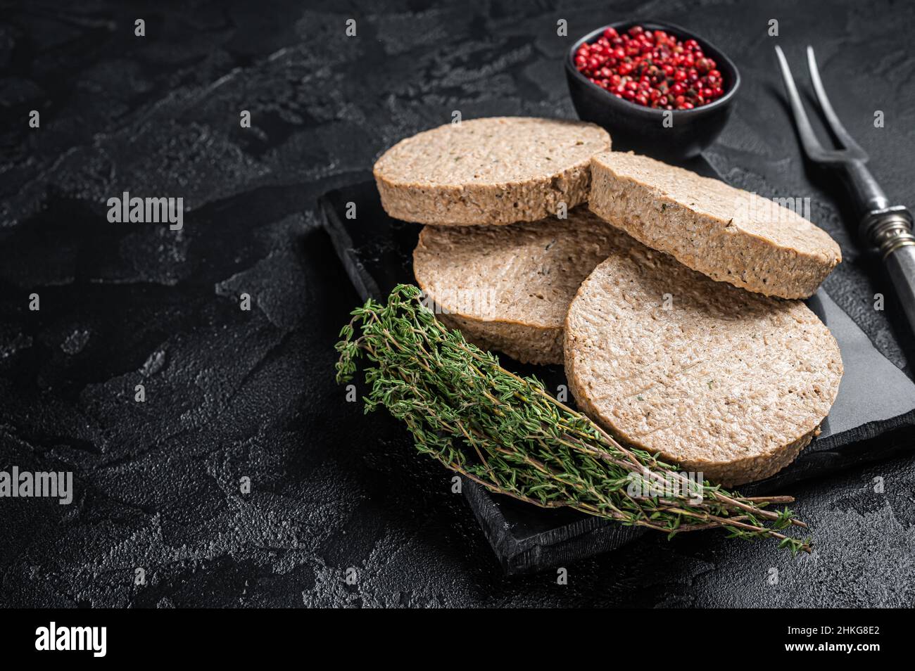 Cotolette di hamburger non cotte a base di carne vegetale, polpette vegane crude. Sfondo nero. Vista dall'alto. Spazio di copia Foto Stock