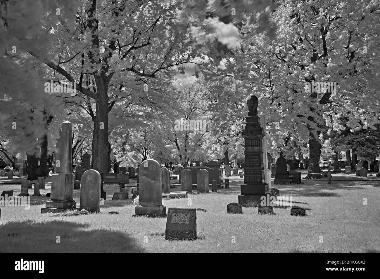 Un cimitero molto vecchio in un cortile della chiesa di riforma inglese del 1776. Questa foto infrarossa, astratta, in bianco e nero è spaventosa e un buon look per Halloween. Foto Stock