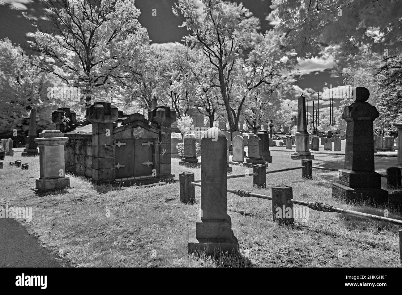 Un cimitero molto vecchio in un cortile della chiesa di riforma inglese del 1776. Questa foto a infrarossi, astratta, in bianco e nero è spaventosa e un buon look per Halloween. Foto Stock
