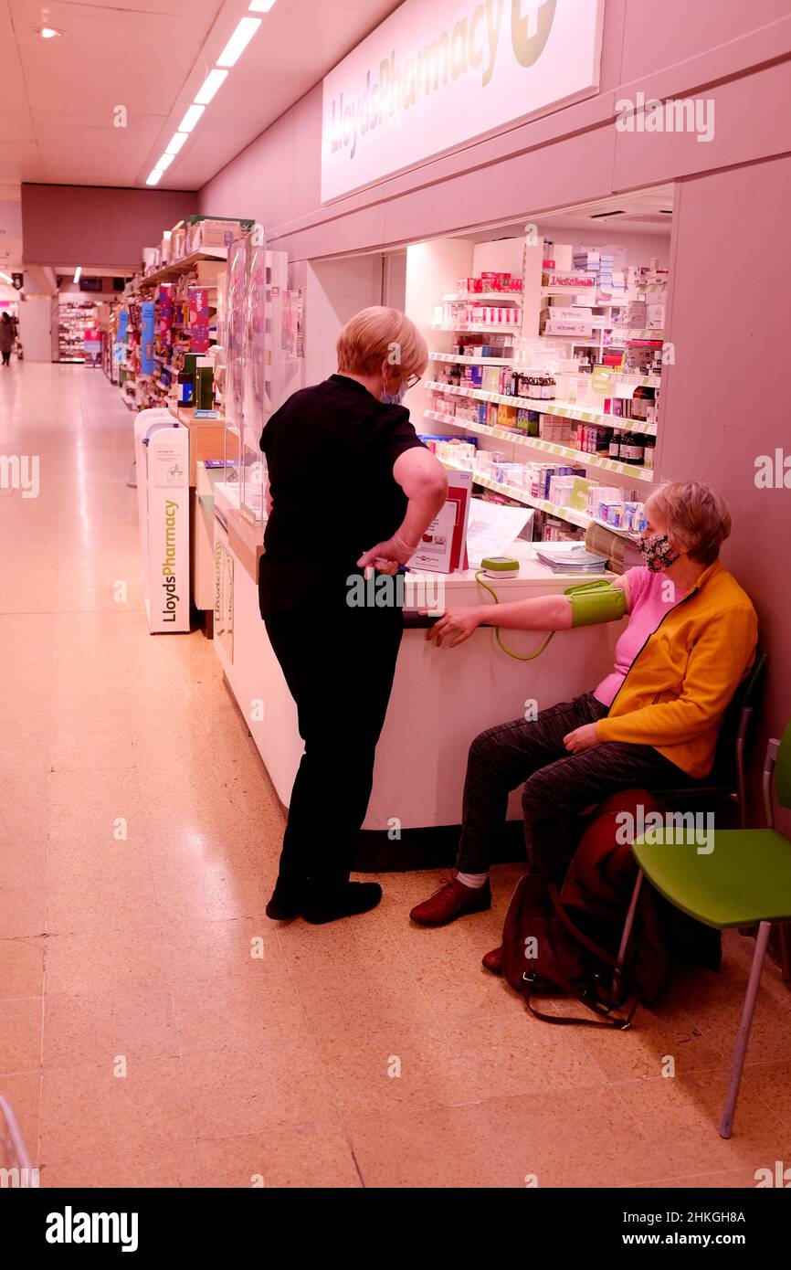donna che ha la sua pressione sanguigna presa alla farmacia di lloyds all'interno del supermercato sainsbury, filiale di northgate, città di canterbury, kent, regno unito febbraio 2022 Foto Stock