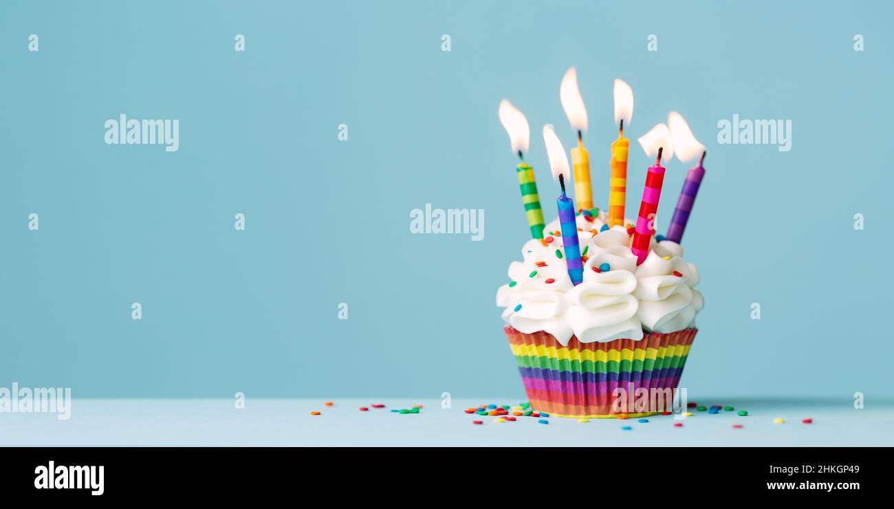 Cupcake di compleanno con un sacco di candele di compleanno colorate su uno sfondo blu con spazio copia a lato Foto Stock