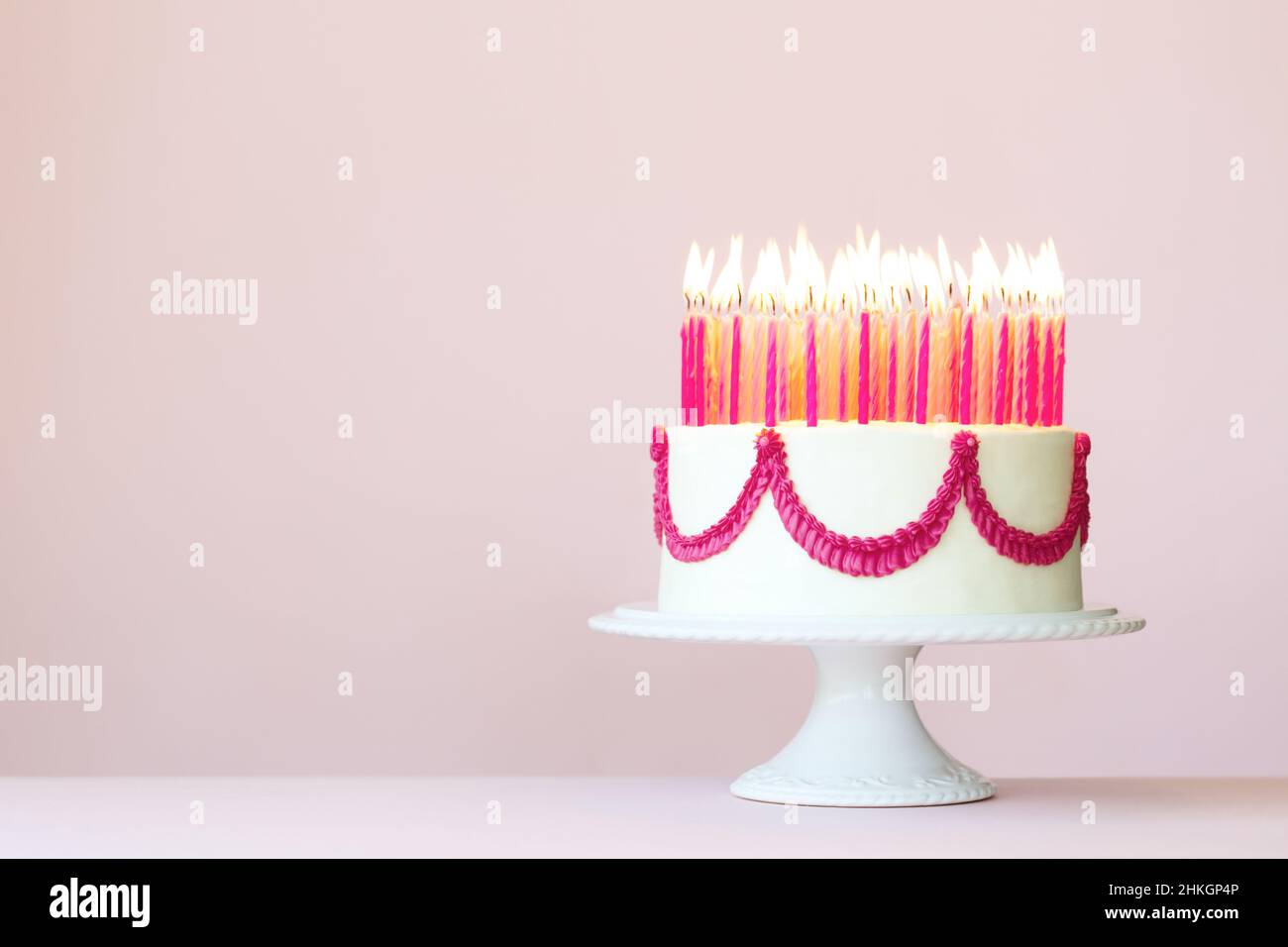 Torta di compleanno con un sacco di candele di compleanno rosa su sfondo rosa Foto Stock