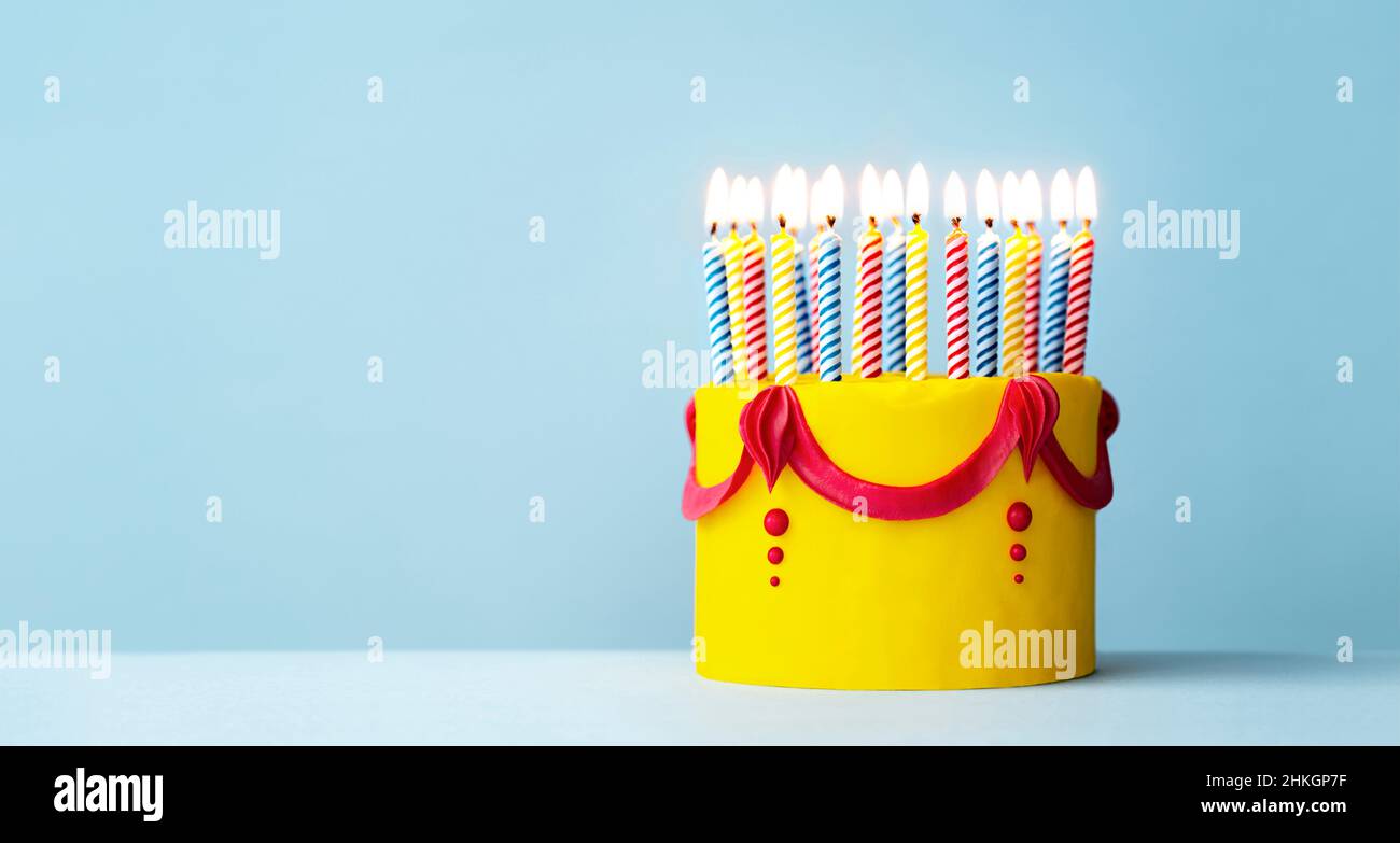Torta di compleanno colorata gialla con un sacco di candele di compleanno e copyspace a lato Foto Stock