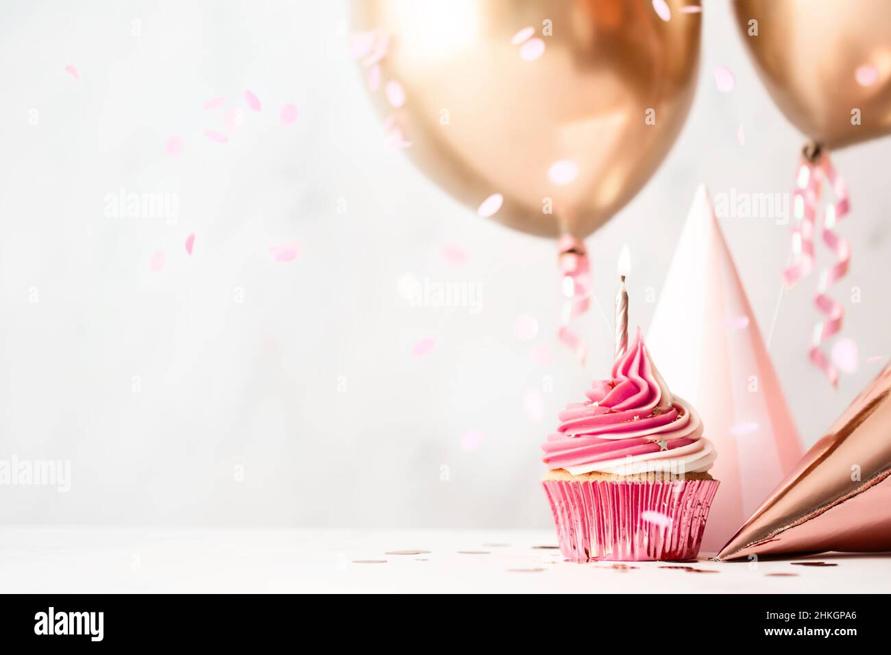 Festa di compleanno con cupcake rosa di compleanno, cappelli da festa e palloncini d'oro rosa Foto Stock