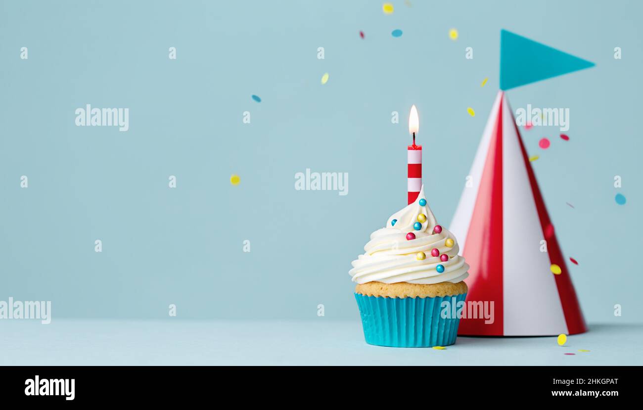 Cupcake di compleanno con una candela di compleanno e cappello da festa a strisce rosso e bianco Foto Stock