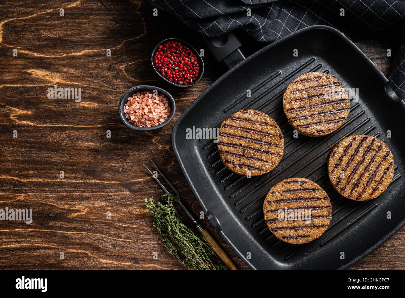 Tortini di hamburger di carne a base di piante vegetariane alla griglia, cotolette di vegano sulla padella alla griglia. Sfondo in legno. Vista dall'alto. Spazio di copia Foto Stock