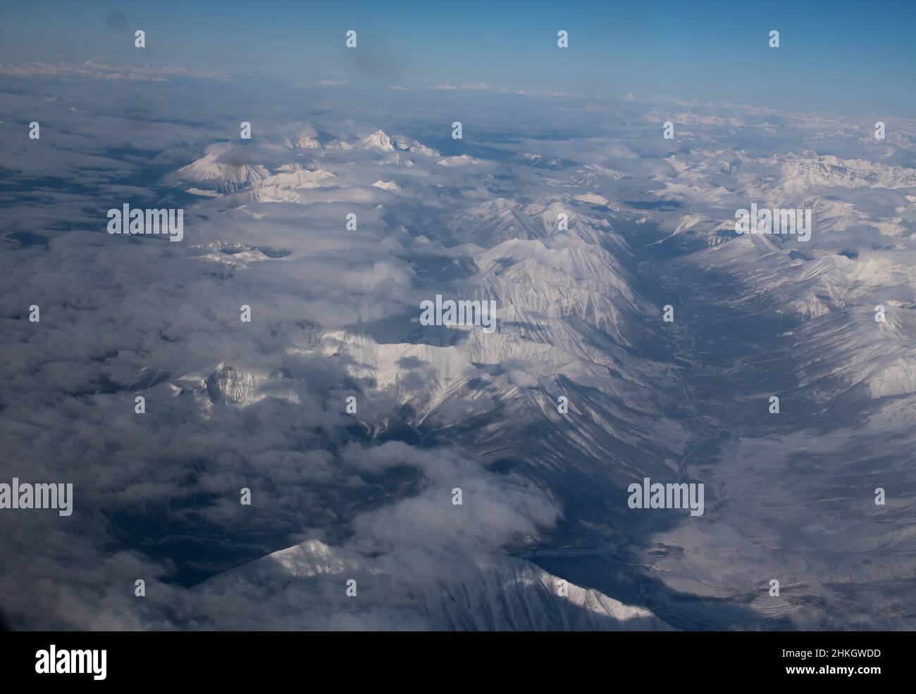 Vista delle montagne rocciose coperte di neve del Canada tra Alberta e British Columbia dalla finestra sede dell'aeroplano su inverni chiari viaggio aereo di giorno Foto Stock