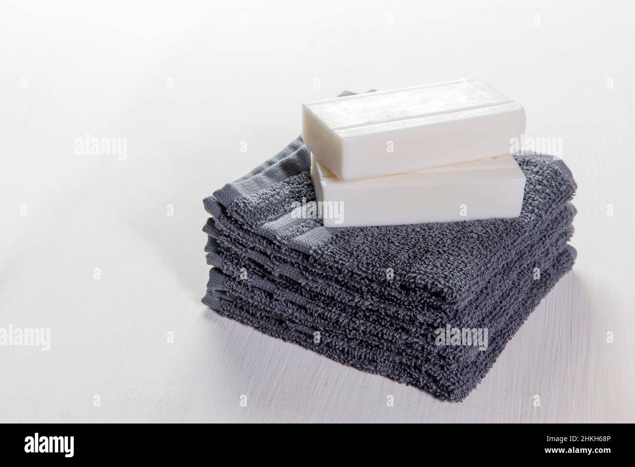Set spa di asciugamani grigi e due pezzi di saponi su sfondo bianco in legno. Set regalo, orientamento orizzontale vista laterale. Concetto di trattamenti Spa. COP Foto Stock