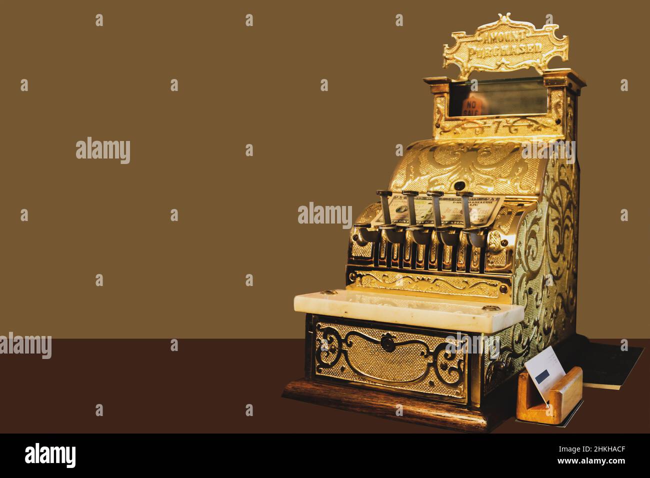 Elegante cassa ornata d'oro sul banco con la fattura posata su di esso e il titolare della carta da visita e ledger accanto ad esso sul banco - stanza per la copia Foto Stock