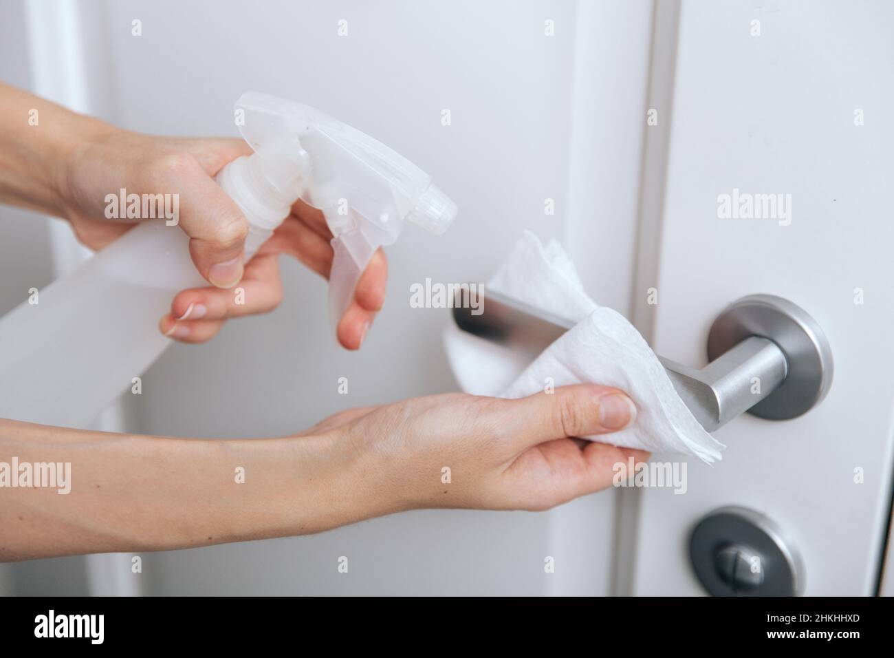 Pulizia delle maniglie bianche dello sportello con una salvietta antisettica bagnata e spray igienizzante. Disinfezione in ospedale e spazi pubblici contro il virus corona. Donna Foto Stock