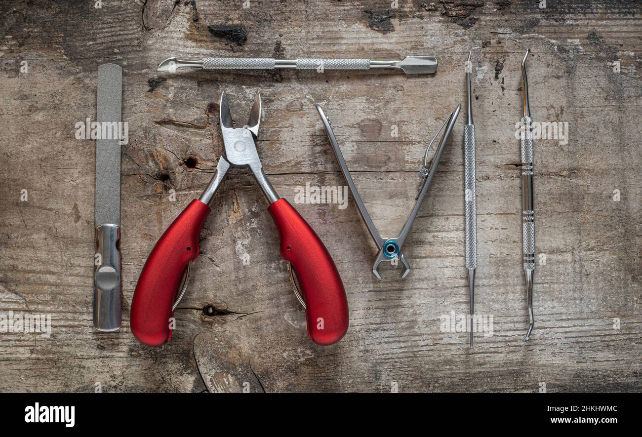 utensili di podiatria su un rustico sfondo di legno tagliatori con manici rossi raccolta di articoli si stendere piatto da sopra Foto Stock