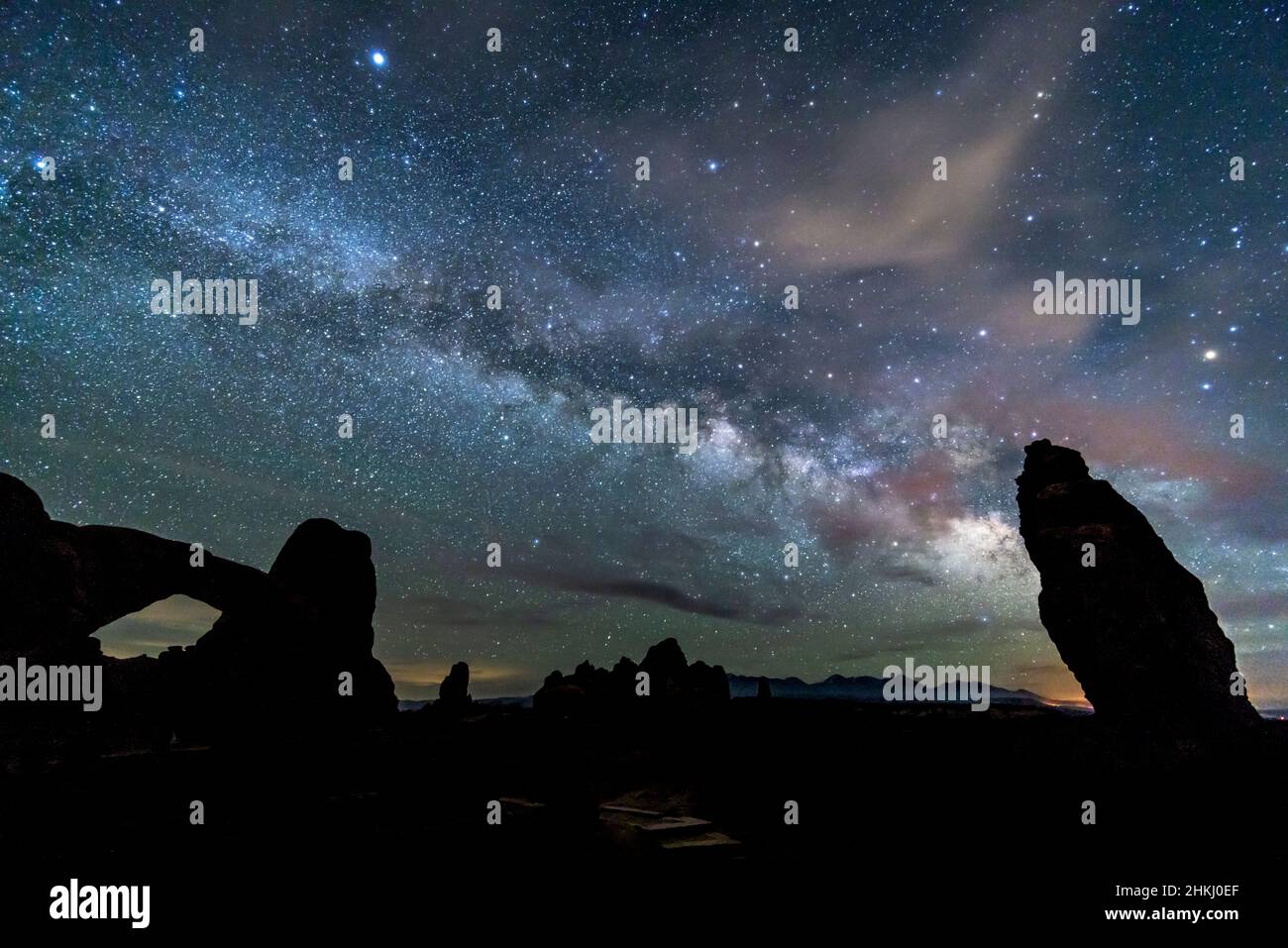 Il cielo notturno pieno di alcune nuvole e la Via Lattea sopra la finestra Nord nelle sezioni Windows di Arches National Park, Utah. Foto Stock