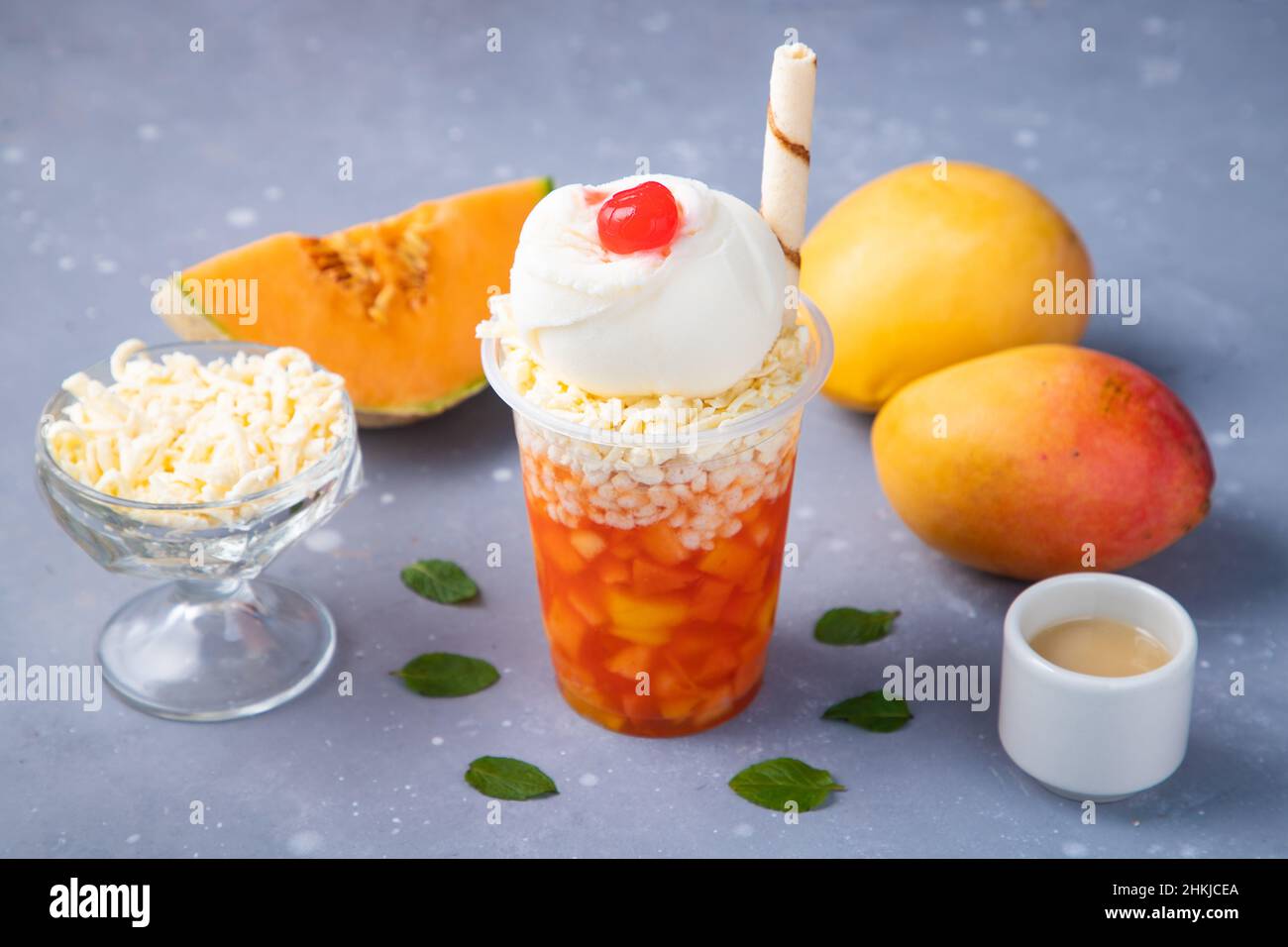 Mango e melone bevanda ghiacciata con gelato decorato su un tavolo grigio Foto Stock