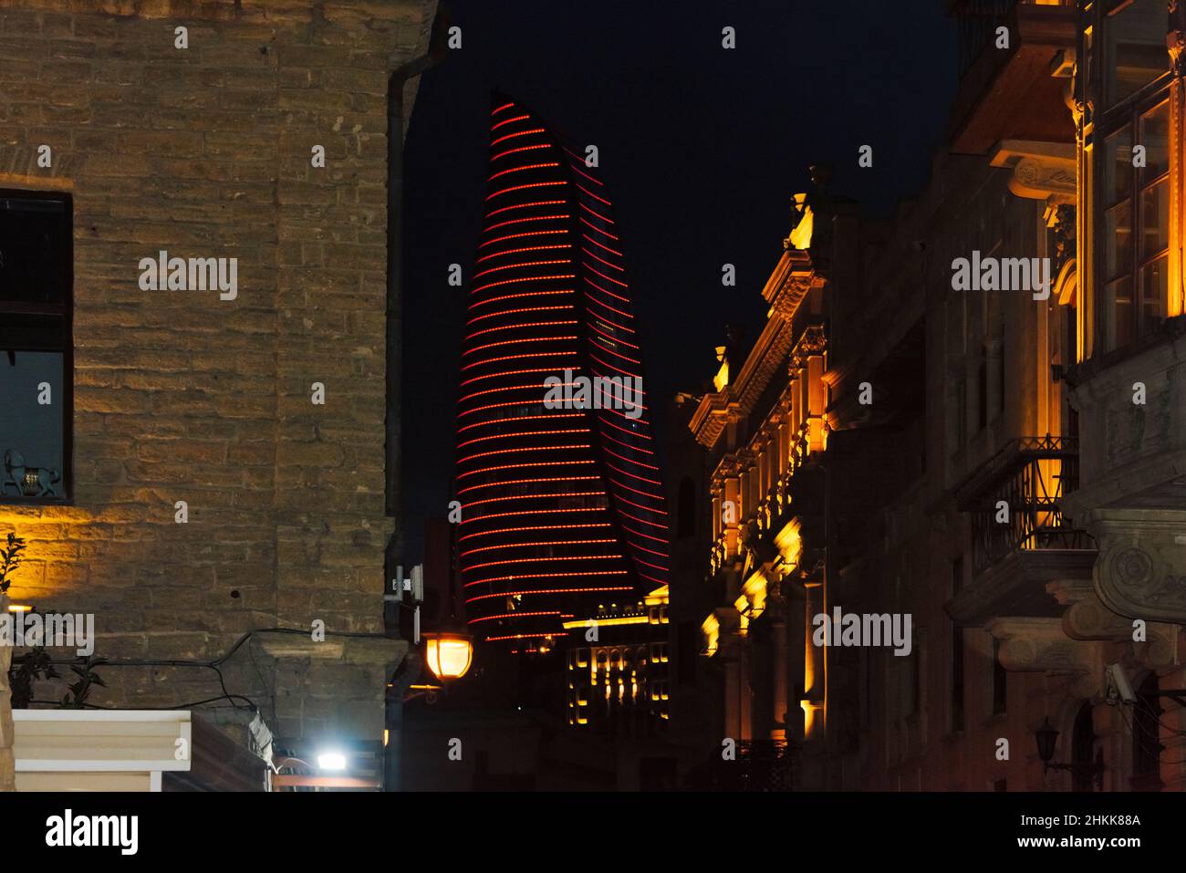 Vista notturna degli edifici tradizionali della Città Vecchia, Torri fiamma in lontananza, Baku, Azerbaigian Foto Stock