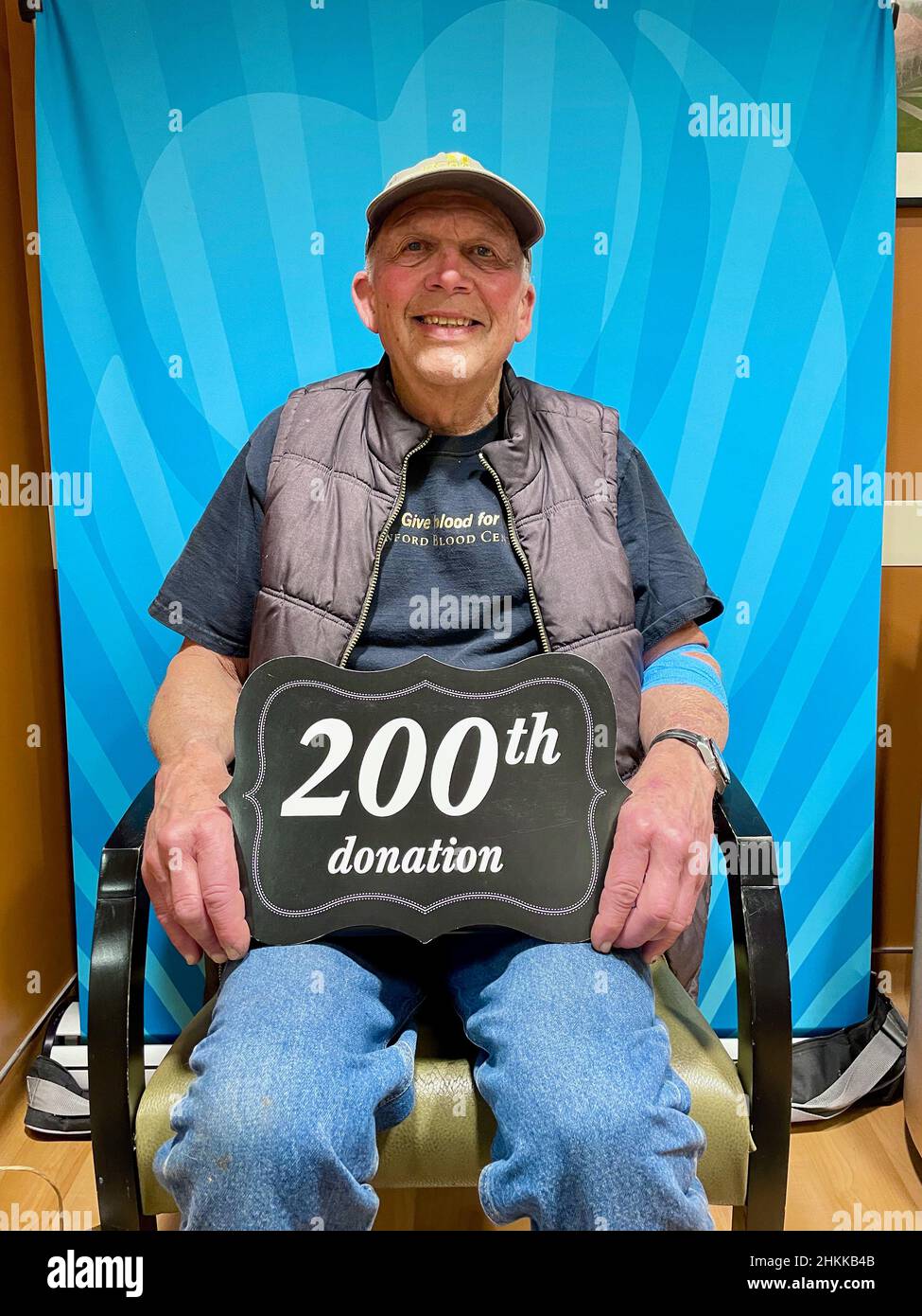 L'uomo caucasico anziano sorride mentre celebra la sua donazione di sangue del 200th. Foto Stock