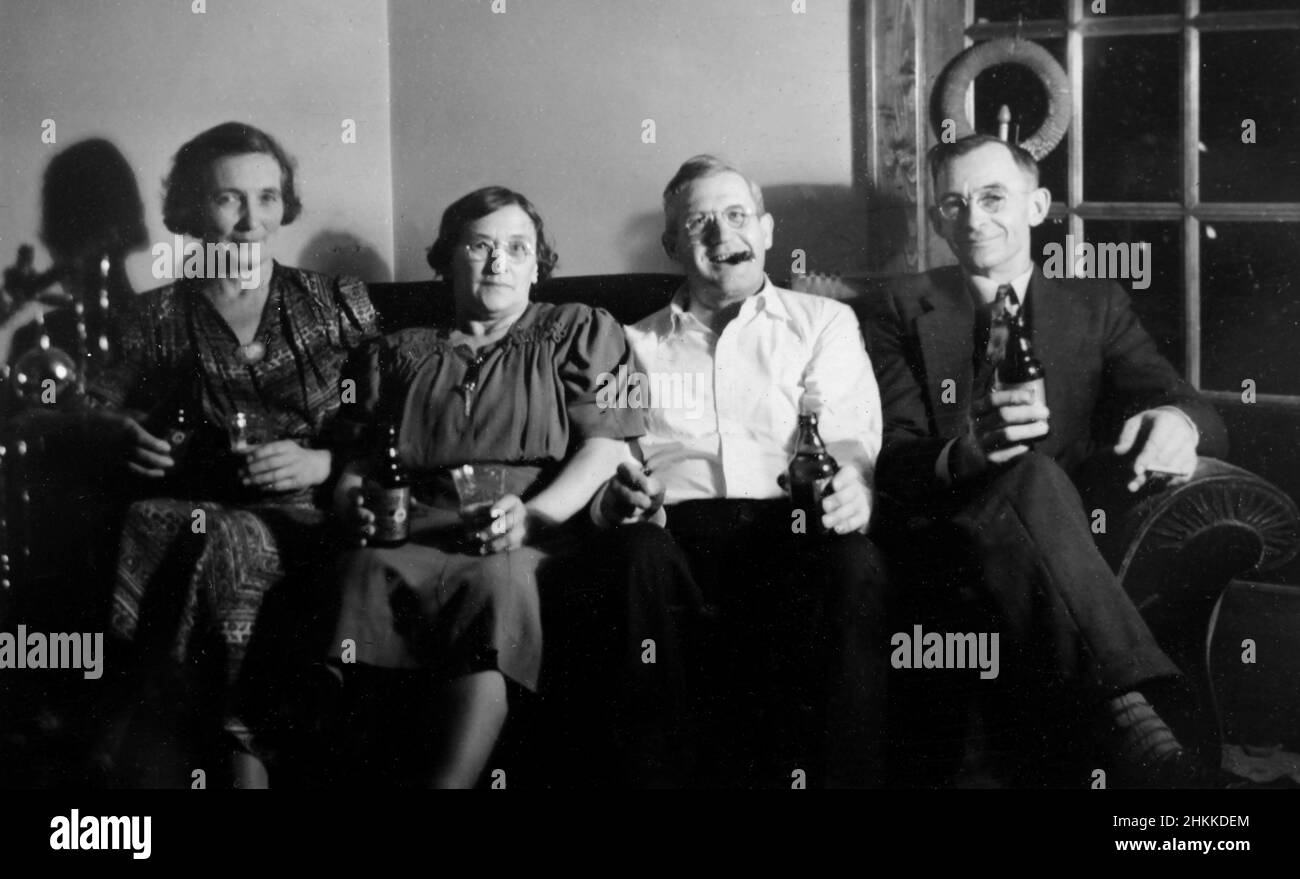 Due coppie anziane si siedono su un divano e sono pronte a fare festa, ca. 1938. Foto Stock