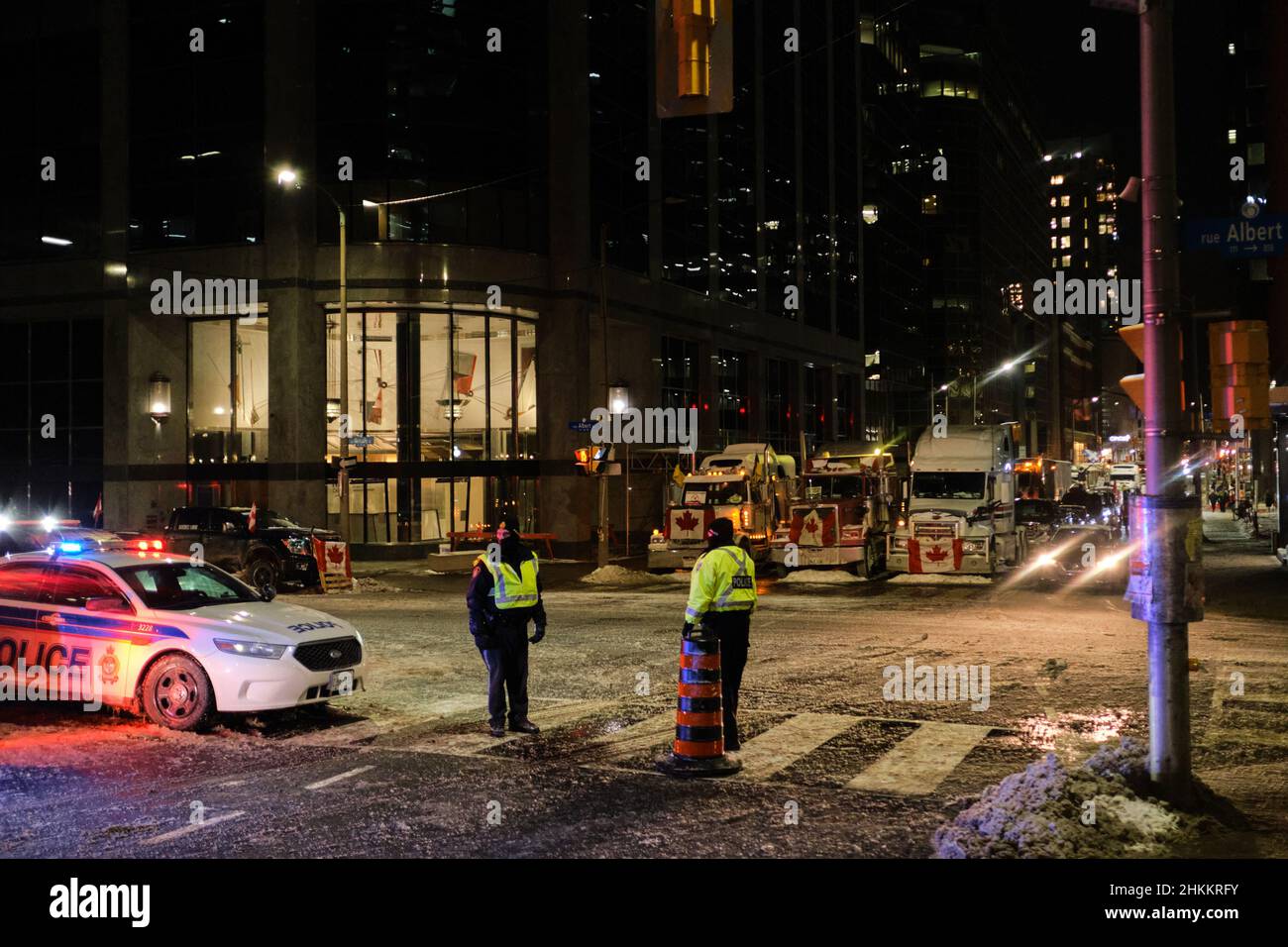 Ottawa, Ontario, Canada - 4 febbraio 2022: Gli ufficiali della polizia di Ottawa si trovano all'incrocio tra Albert e Metcalfe, come camion di protesta del convoglio della libertà Foto Stock