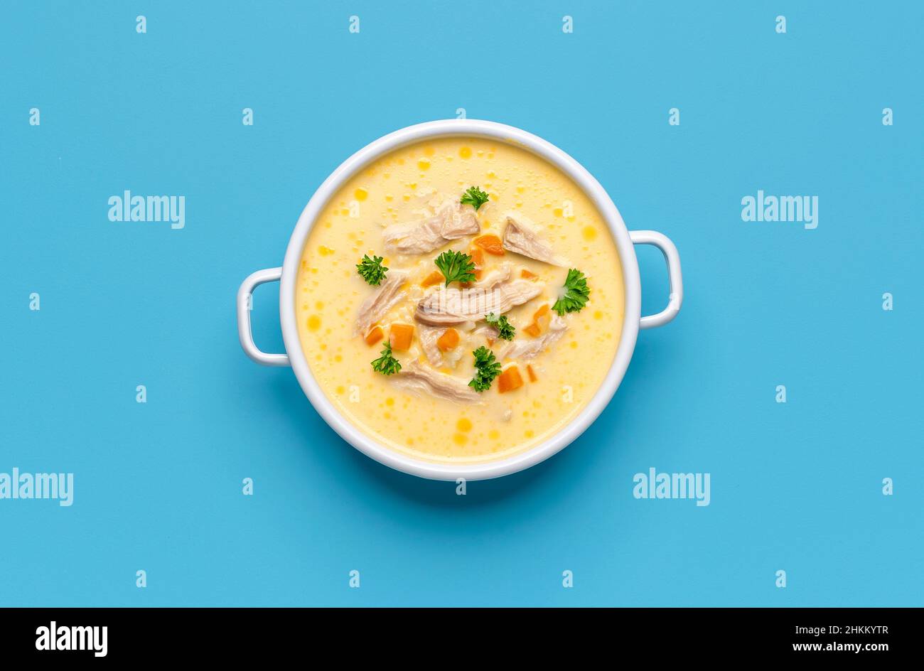 Vista dall'alto con una ciotola di zuppa di pollo greca minimalista su un tavolo blu. Deliziosa zuppa di avgolemono, a base di carne di pollo, limone, uova e riso Foto Stock