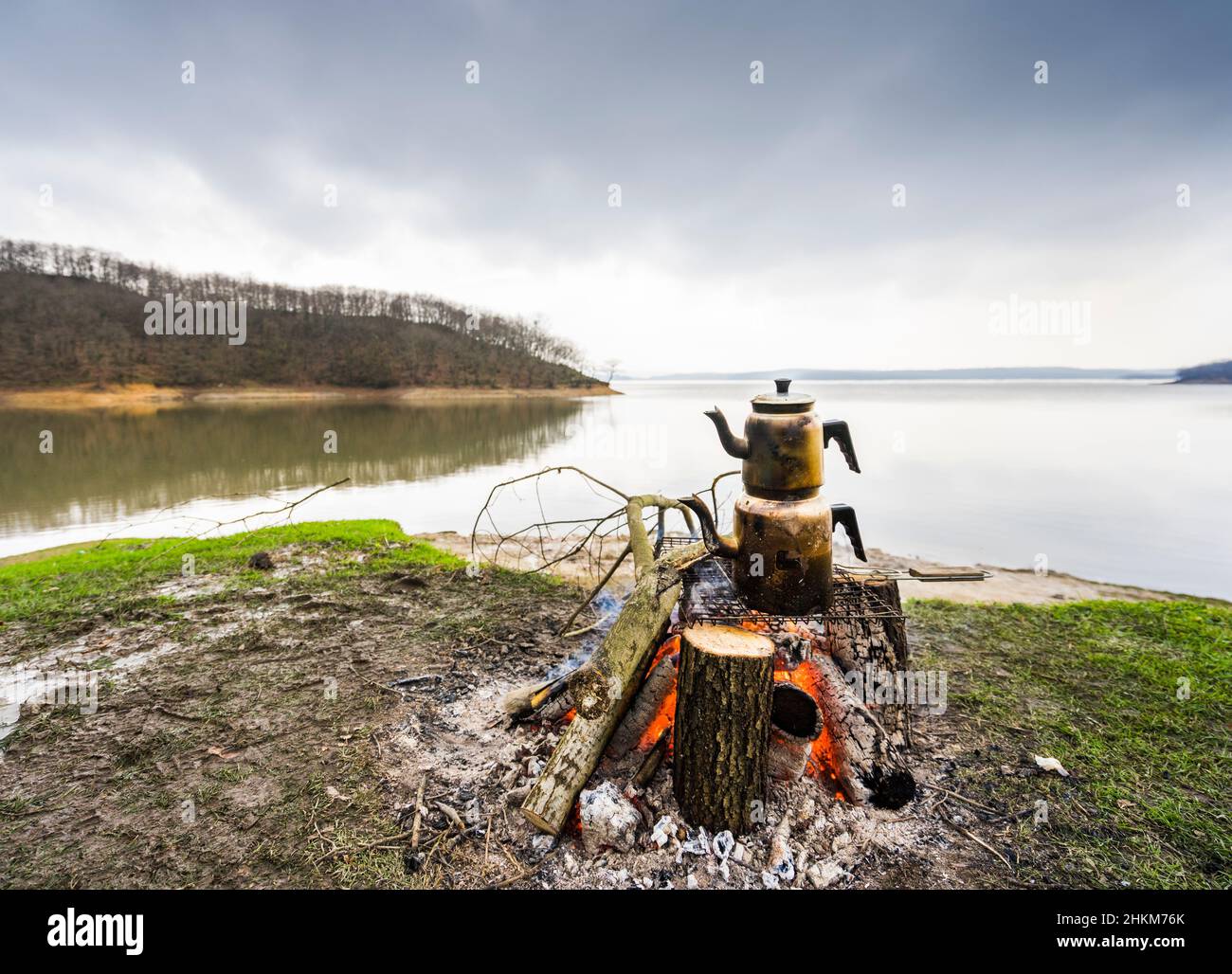 Teiera turca tradizionale bollente sul fuoco, un lago liscio sullo sfondo. Foto Stock