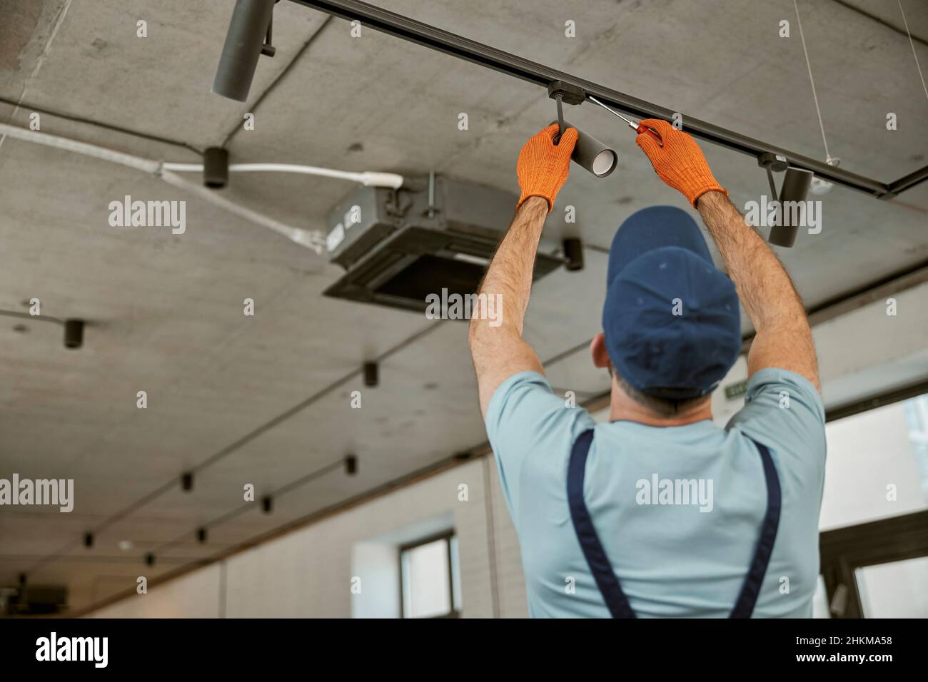 Elettricista maschio che fissa la lampada da soffitto nell'edificio Foto Stock