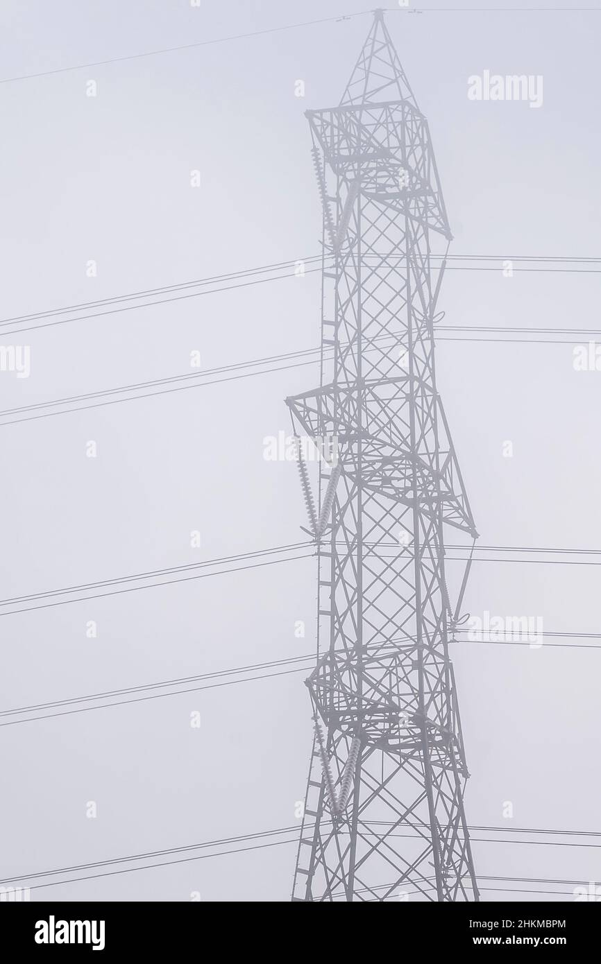 Un grande traliccio ad alta tensione è protetto dalla nebbia mattutina Foto Stock