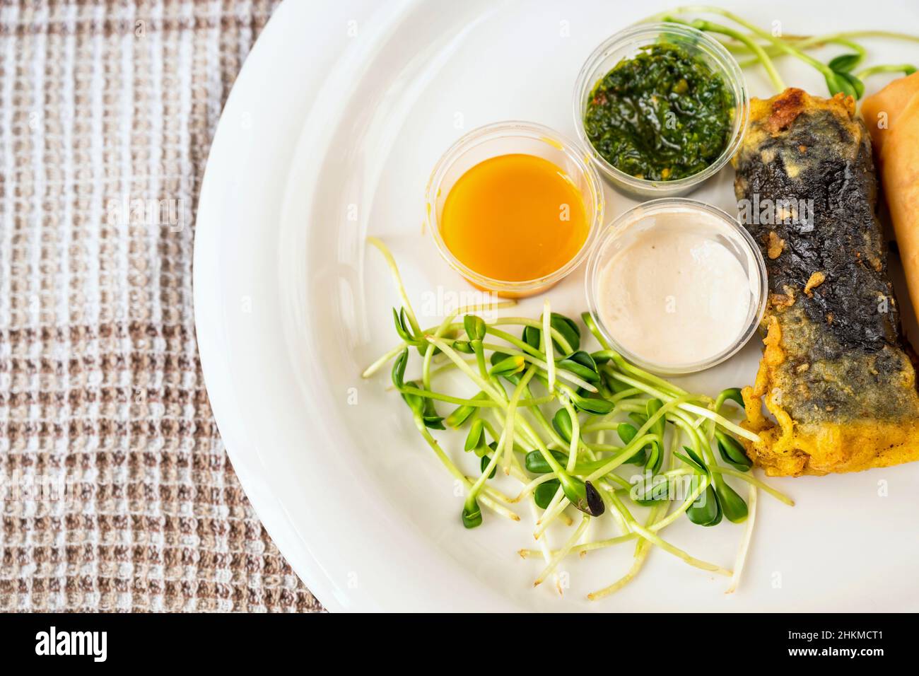 Piatto con verdure germogliate, 3 ciotola con salsa, rotolo vietnamita con alghe, closeup. Pasto vegetariano o vegano. Foto Stock