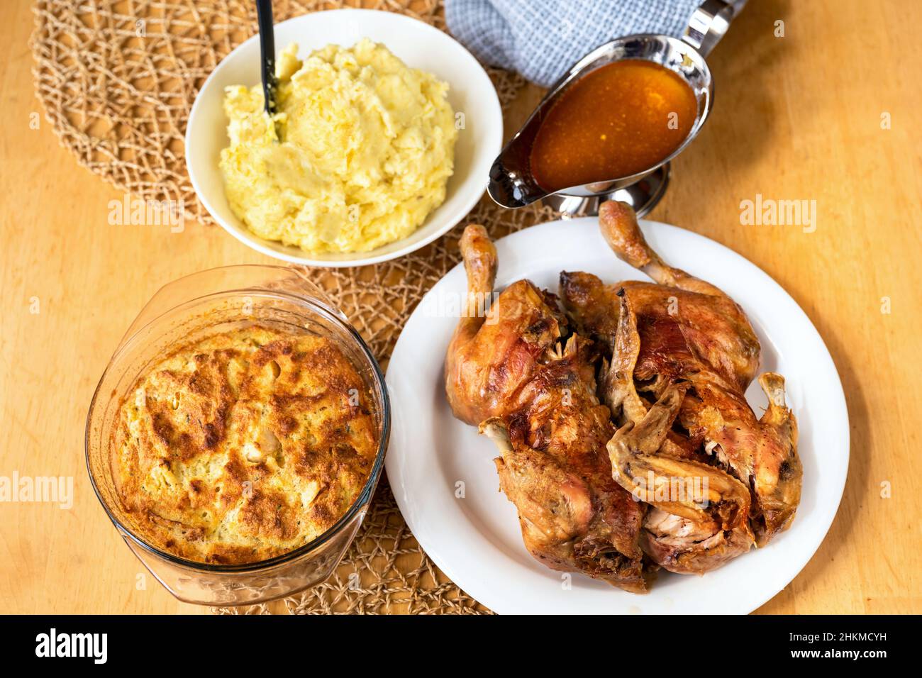 Pollo al forno sul piatto, uova al forno e ripieno in una ciotola di vetro, purè di patate e salsa in pentola su tavola di legno. Foto Stock