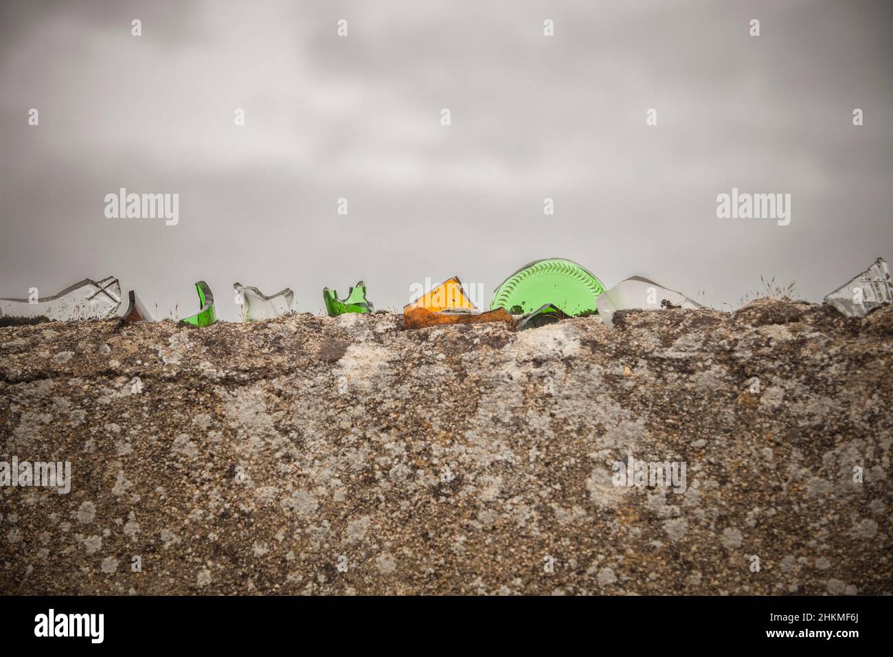 Parete coperta di vetro colorato rotto. Pezzi affilati intarsiati su mortaio Foto Stock