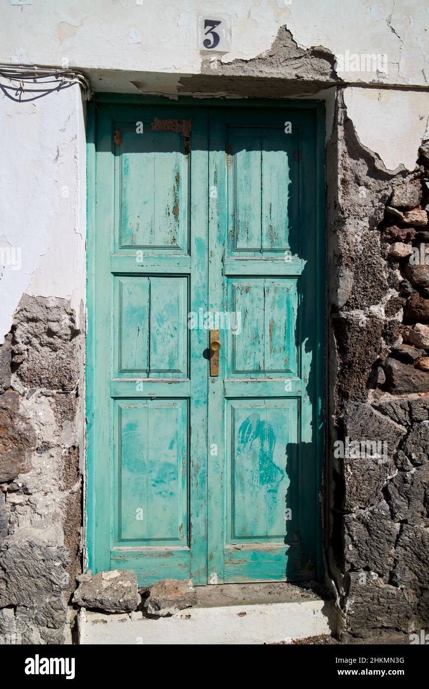 Porta di legno verde sulla costruzione tipica casa delle canarie con render rotto per rivelare la costruzione di roccia vulcanica Teguise Lanzarote Isole Canarie SPAI Foto Stock